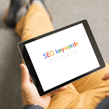 Una persona sostiene una tableta que dice palabras clave SEO en la pantalla.