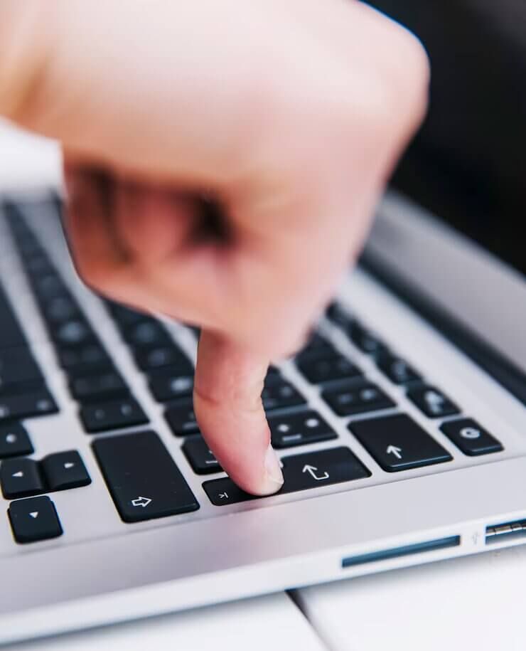 Una persona está escribiendo en una computadora portátil con el dedo en la tecla Enter