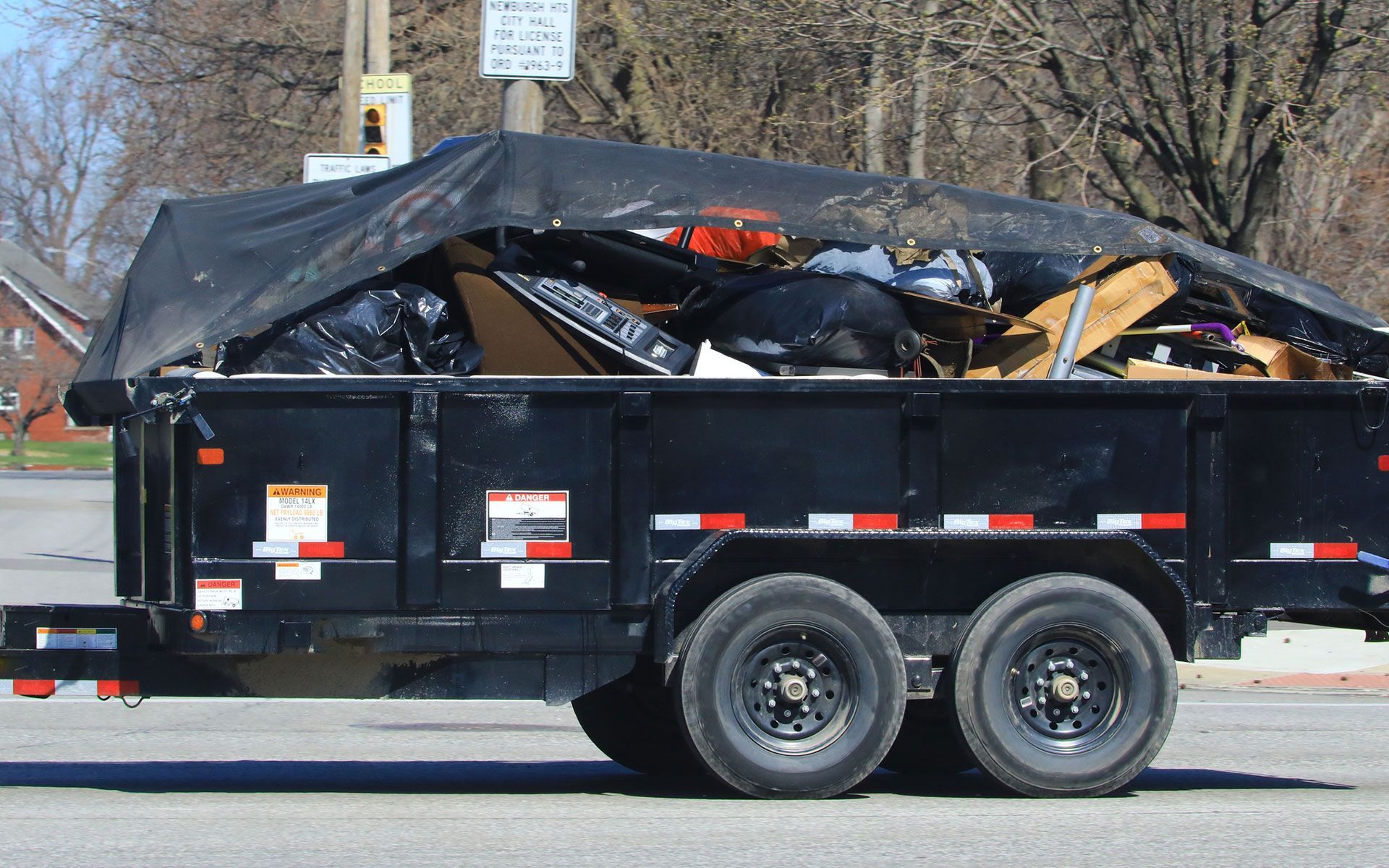 A dumpster trailer filled with trash is parked on the side of the road.