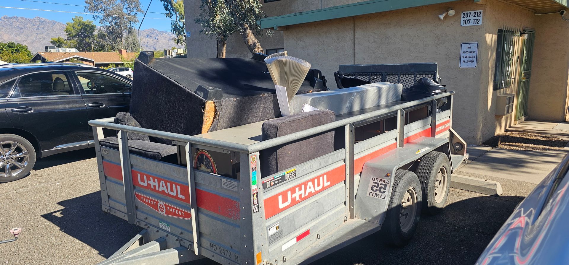 A dumpster truck is driving down a street in front of a house.