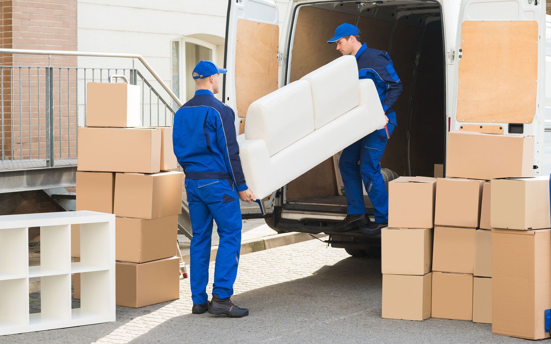 Two men are loading a couch into a moving van.