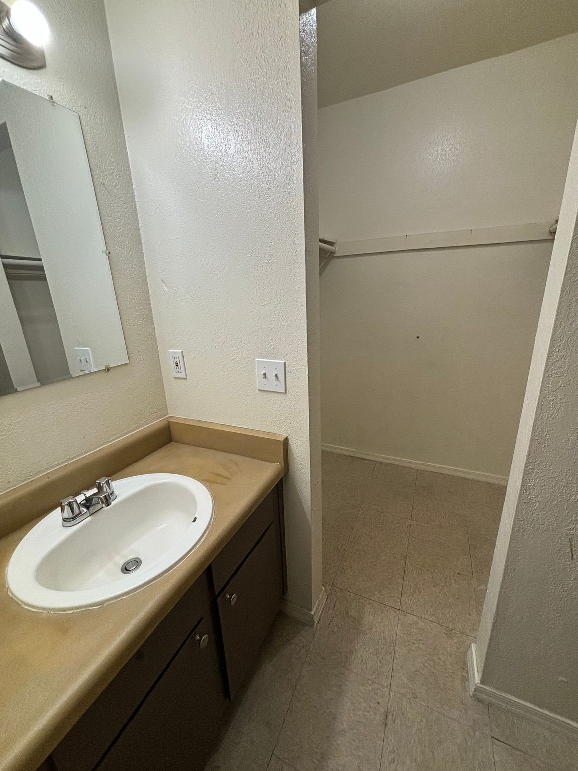 A bathroom with a sink , mirror and walk in closet.