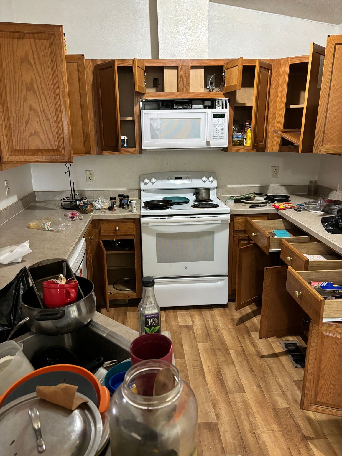 A kitchen with a stove , microwave , sink and cabinets.