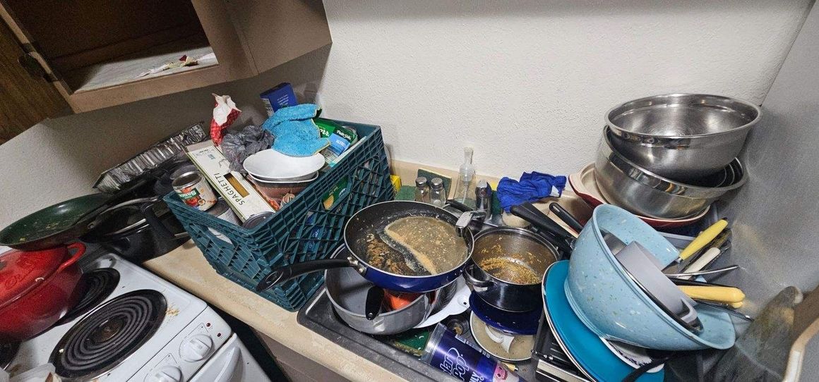 A bunch of dirty dishes are sitting on a counter in a kitchen.