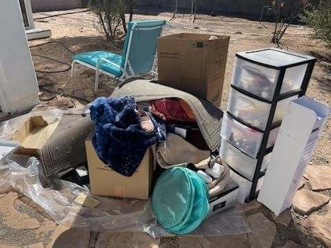 A pile of boxes , chairs , dressers , and other items on the ground.