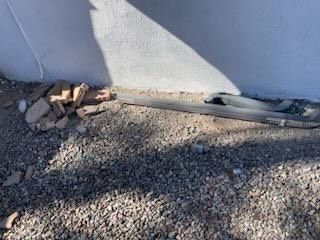 A hose is laying on the ground next to a wall.