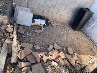 A pile of rocks is laying on the ground in front of a brick wall.