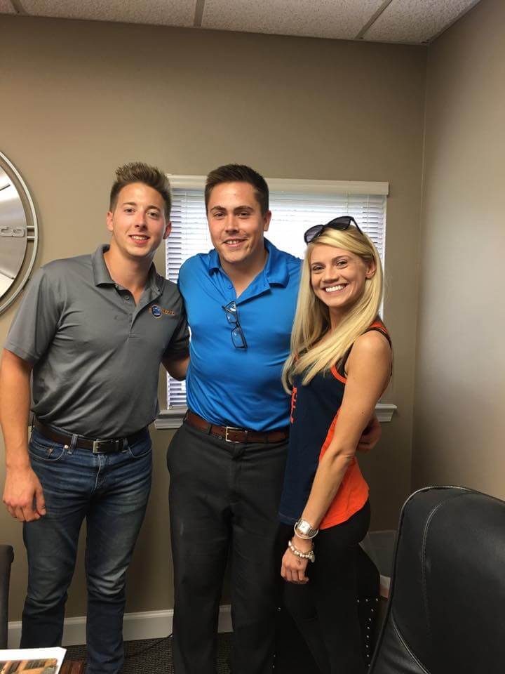 A man and two women are posing for a picture in an office.