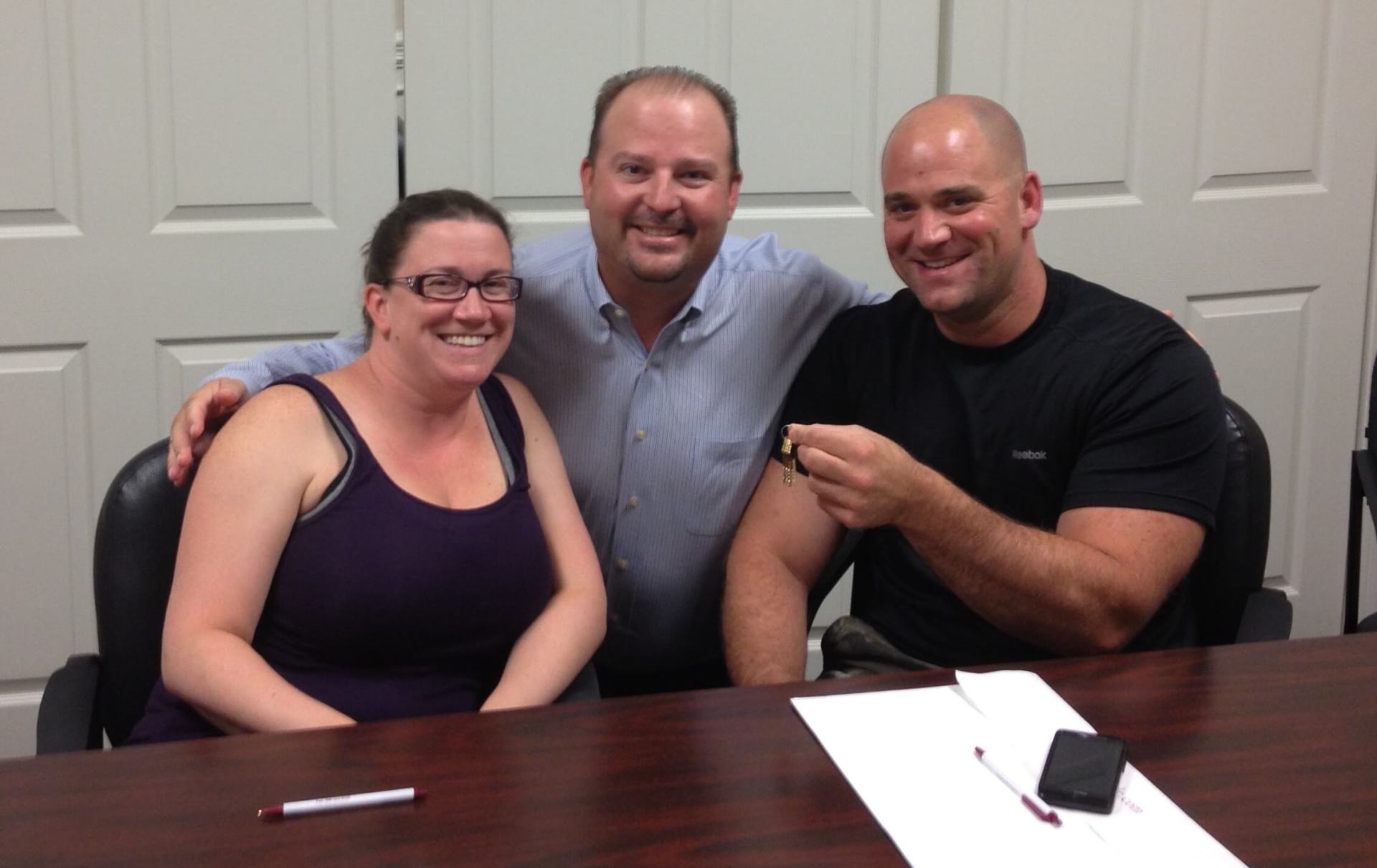 Two men and a woman are posing for a picture at a table