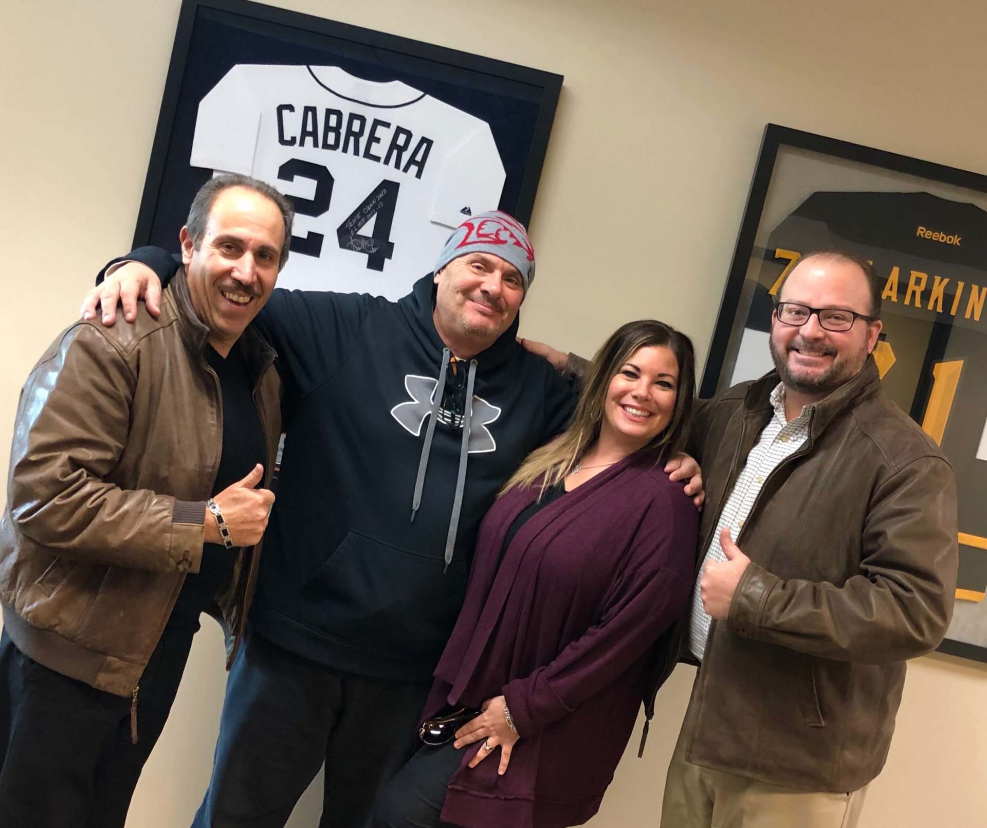 A group of people posing for a picture in front of a jersey that says cabrera 24