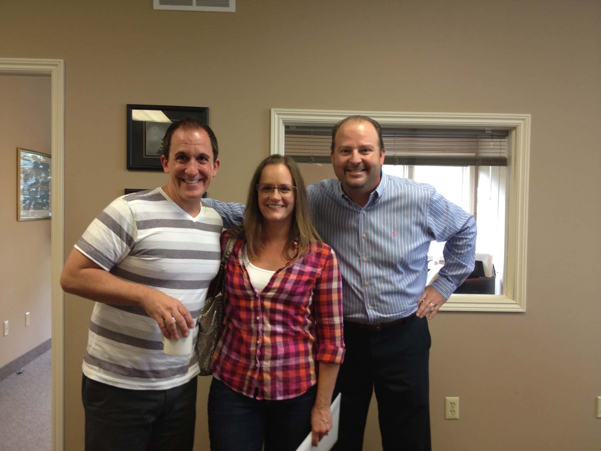 Three people posing for a picture in front of a window