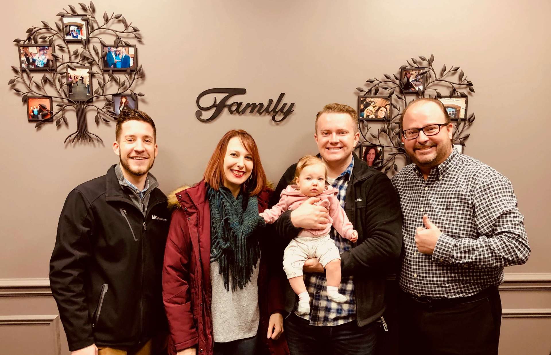 A group of people are posing for a picture in front of a wall that says `` family ''.