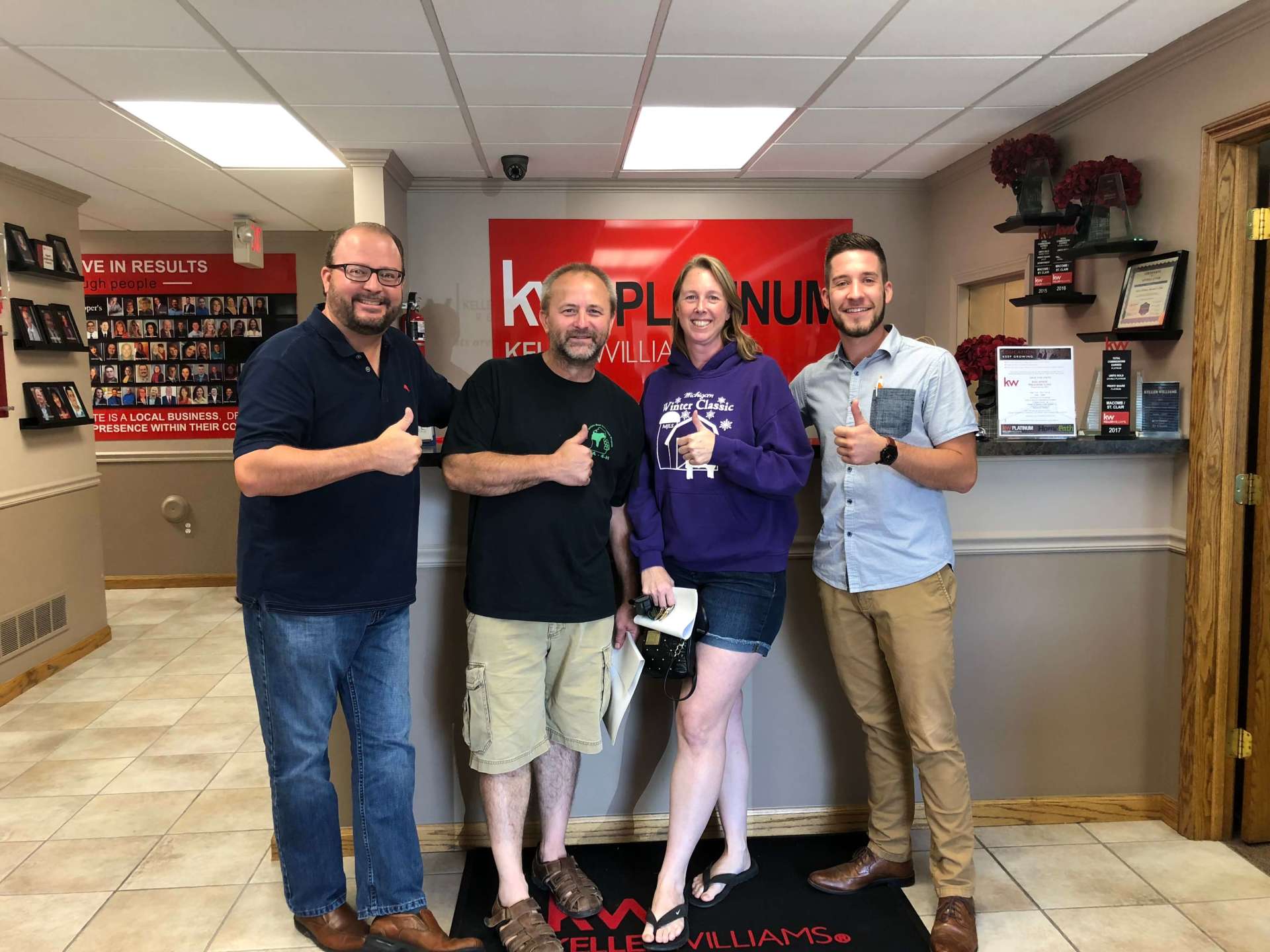 A group of people standing next to each other in a room giving a thumbs up.