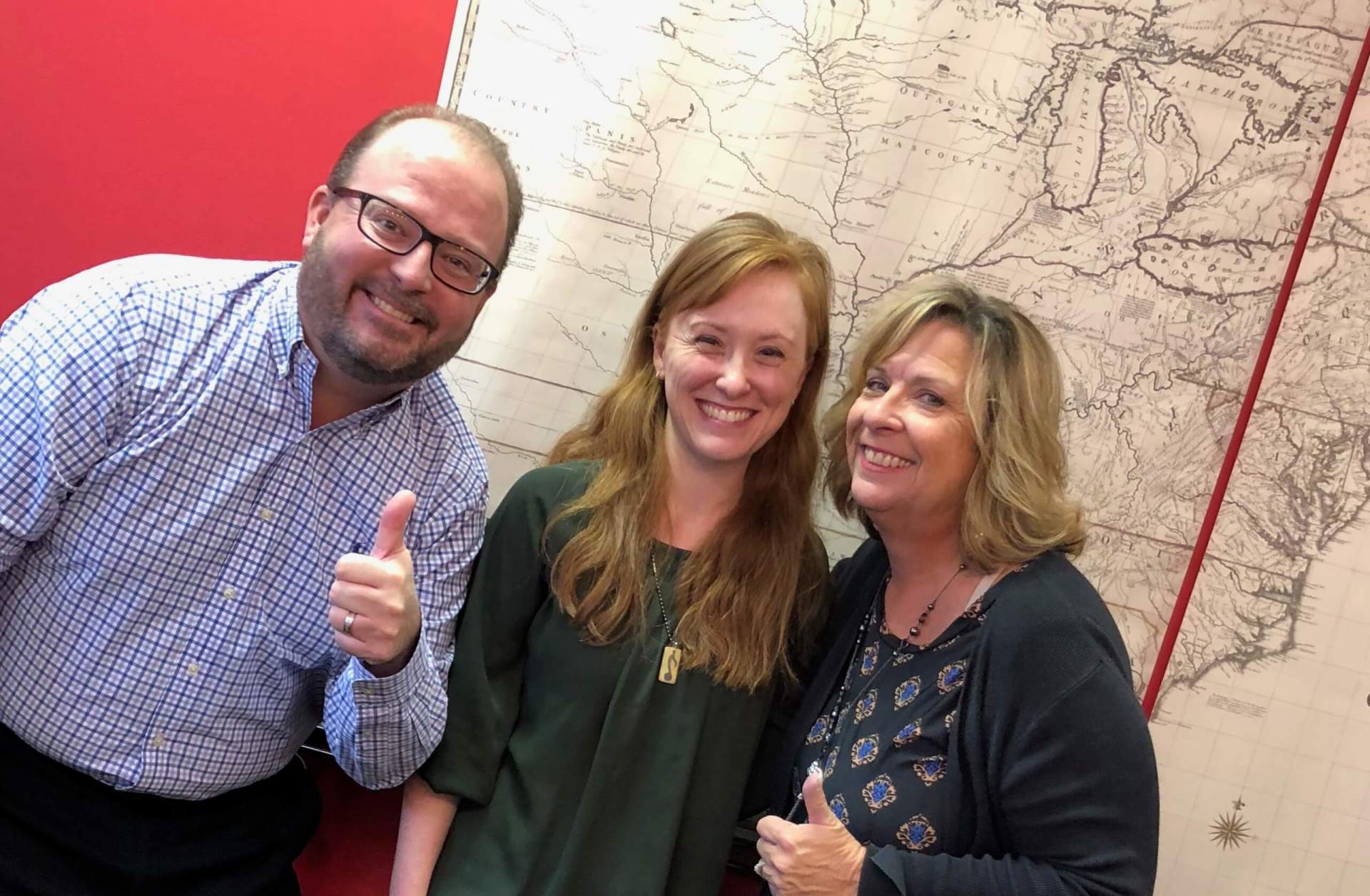 A man and two women are standing next to each other and giving a thumbs up.