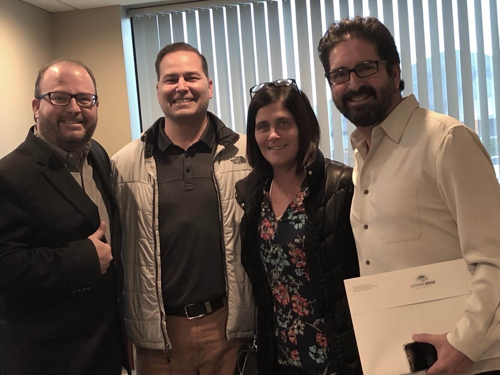 A group of people posing for a picture in front of a window