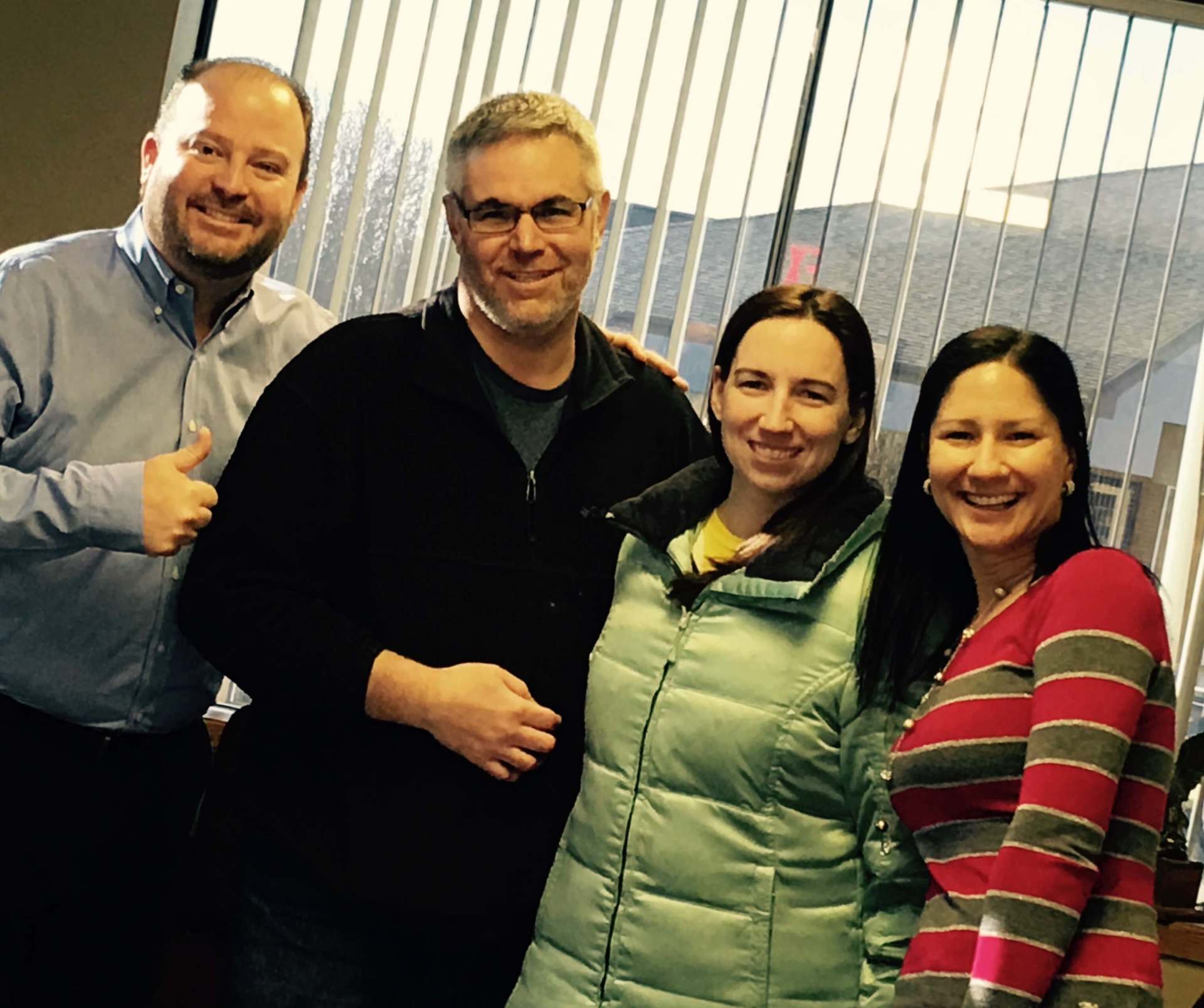 A group of people posing for a picture in front of a window