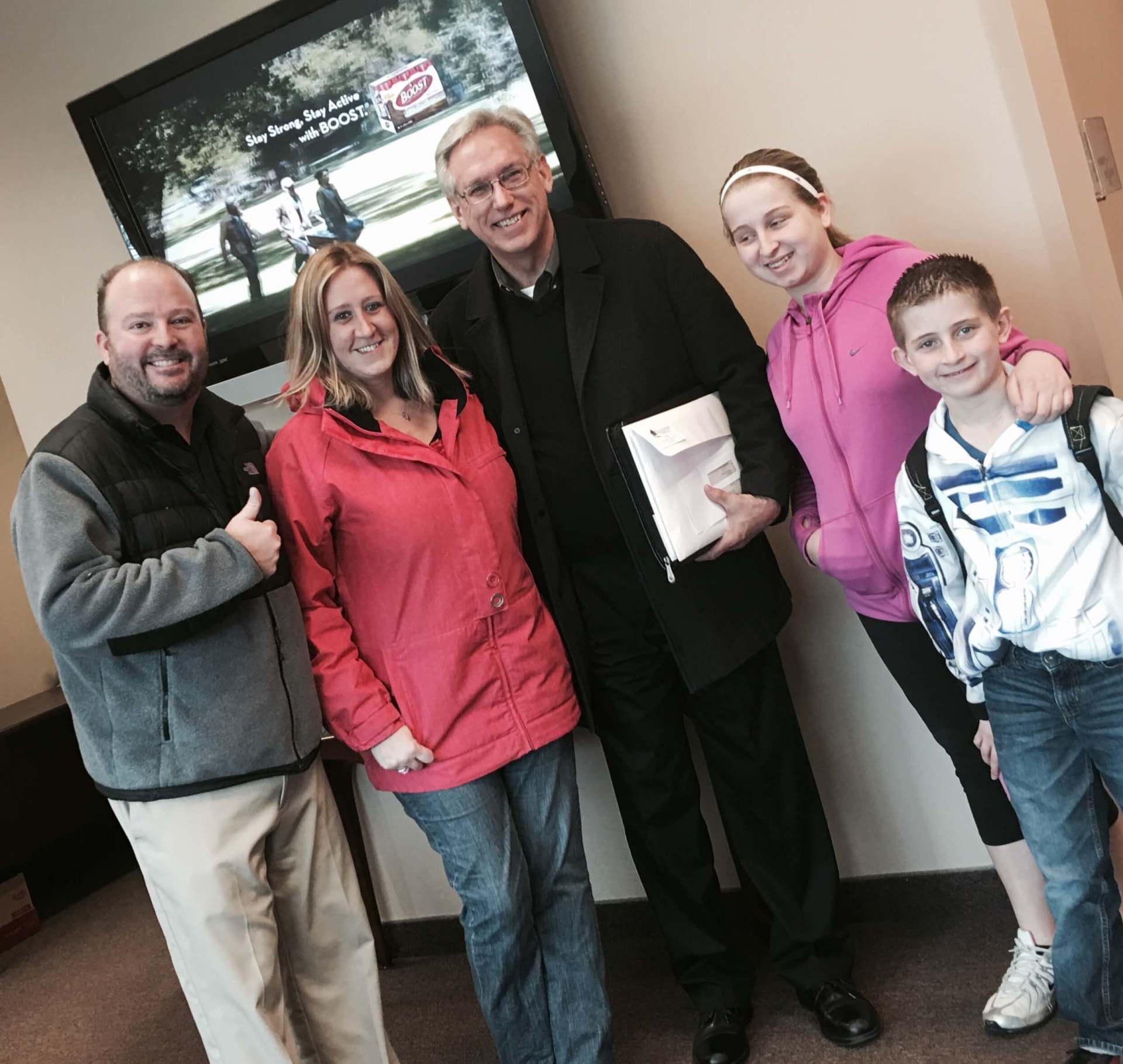 A group of people posing for a picture in front of a flat screen tv