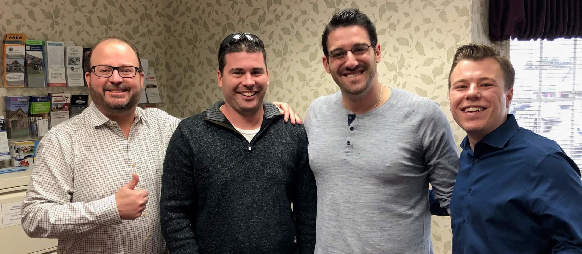 A group of four men are posing for a picture in a room.