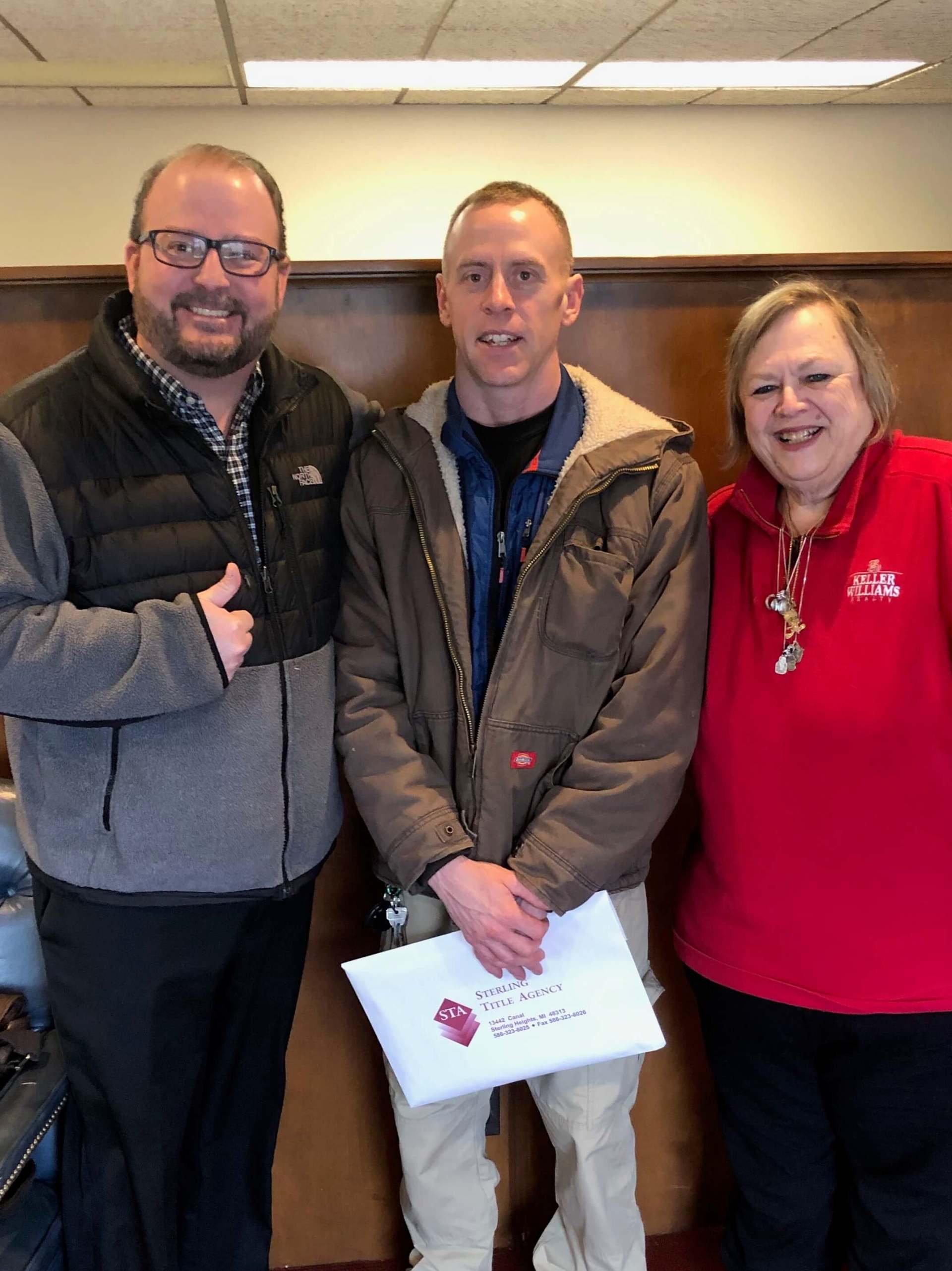 Two men and a woman are posing for a picture in a room.