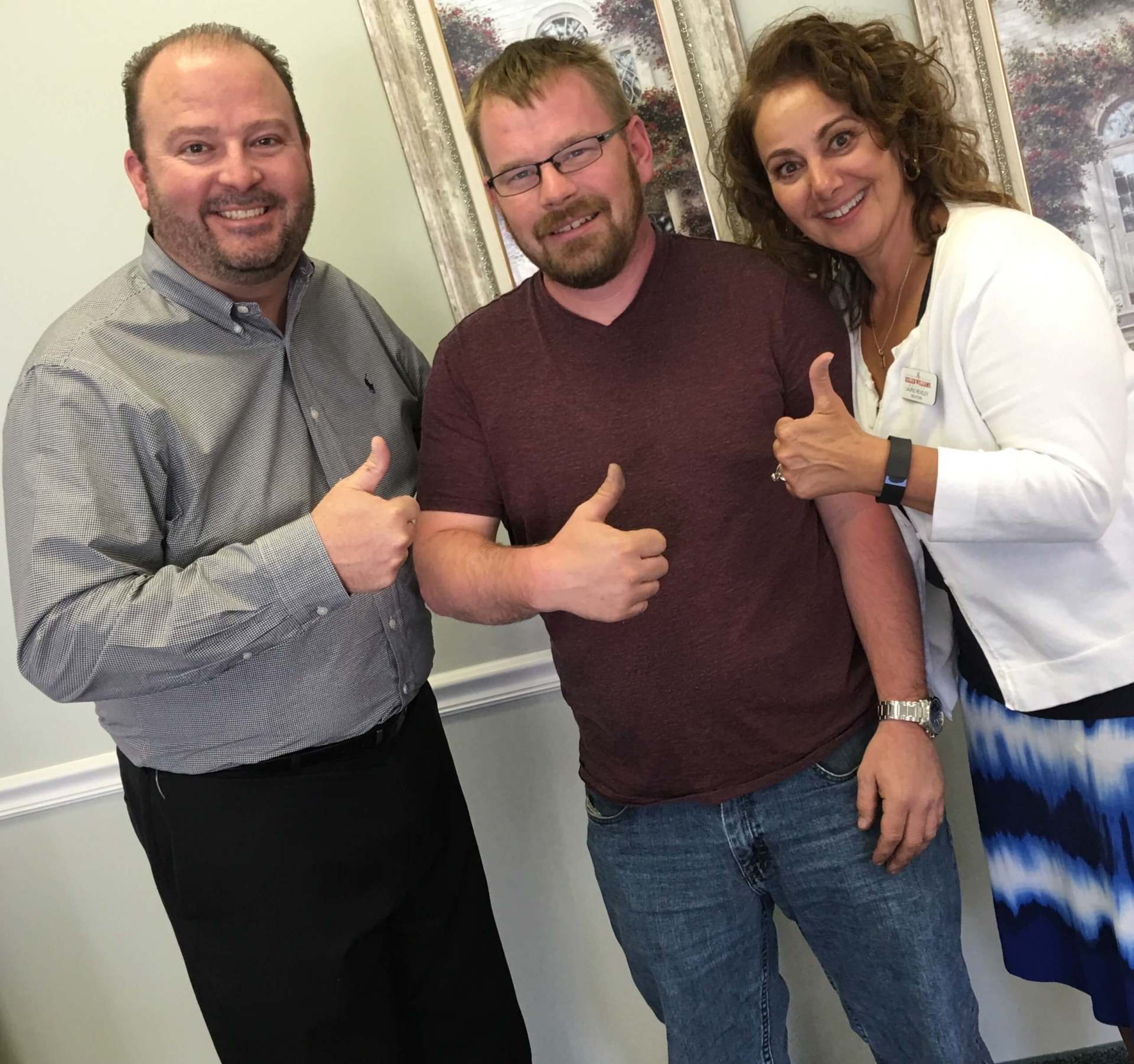 Three people are posing for a picture and one of them is giving a thumbs up.