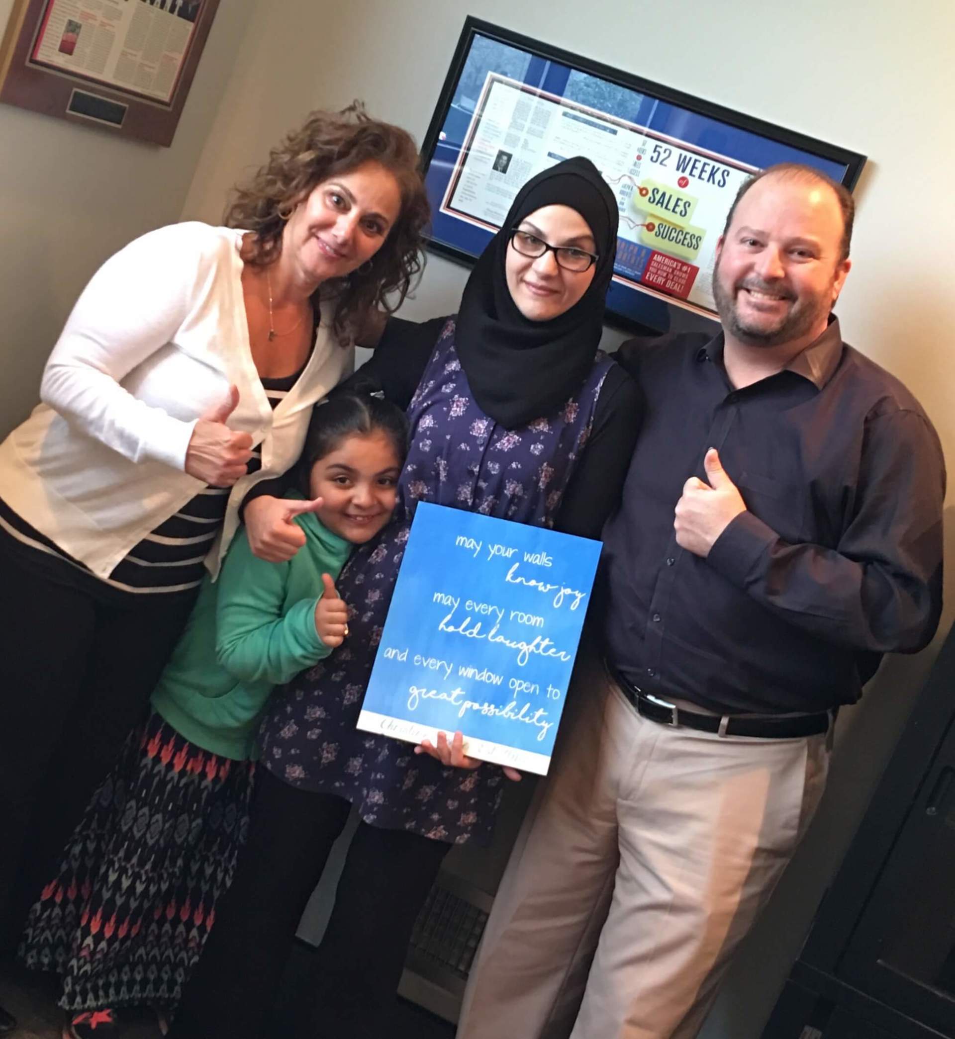 A group of people are posing for a picture and one of them is holding a sign.