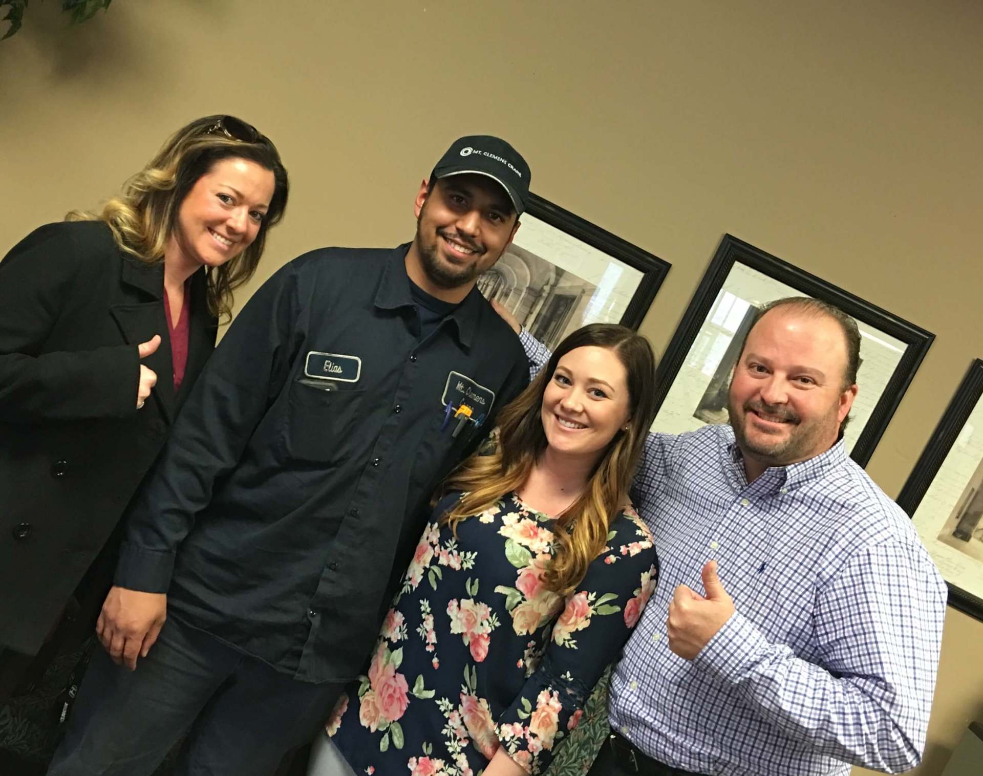 A group of people are posing for a picture and one of them is giving a thumbs up.