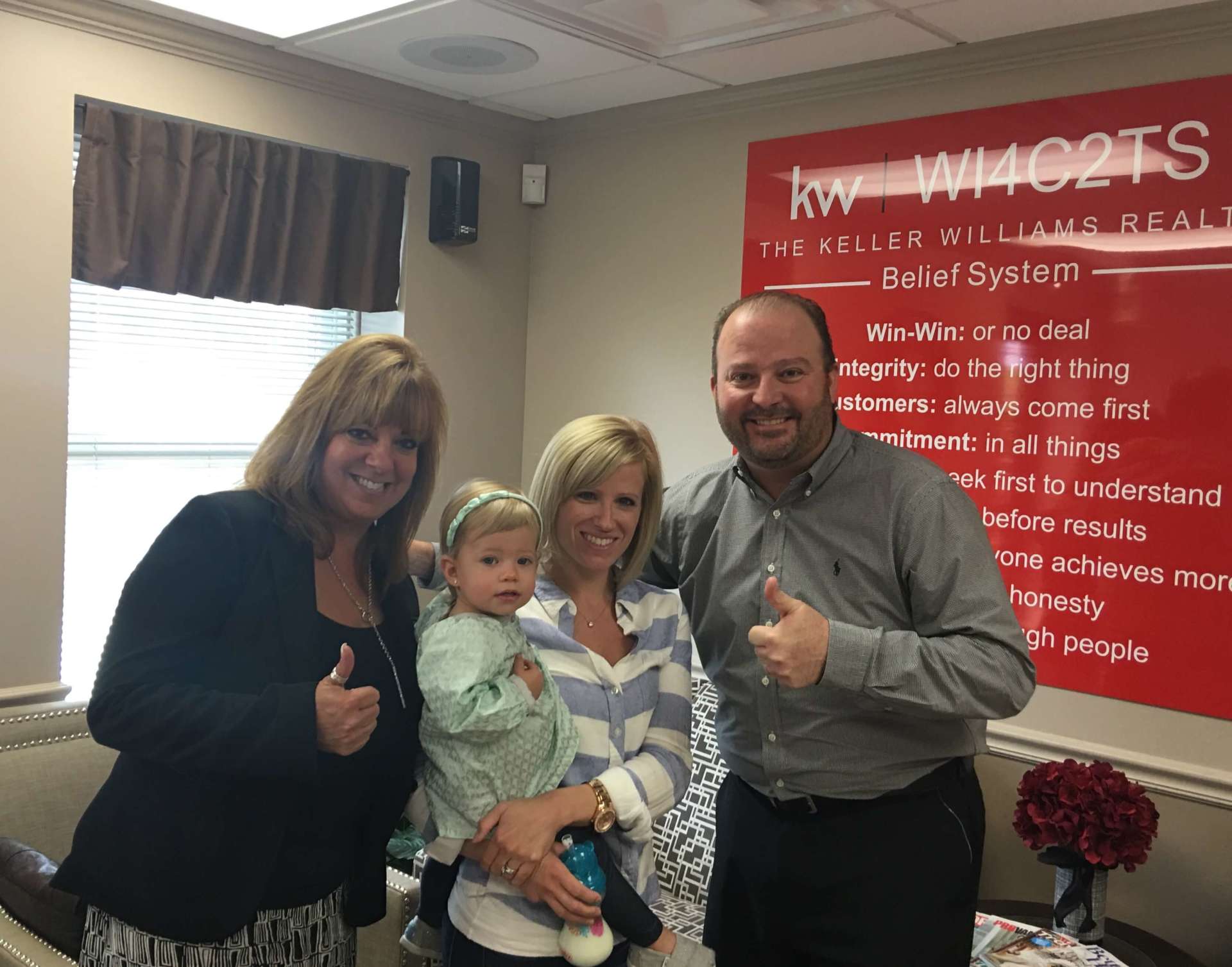 A group of people are posing for a picture in front of a red wall.