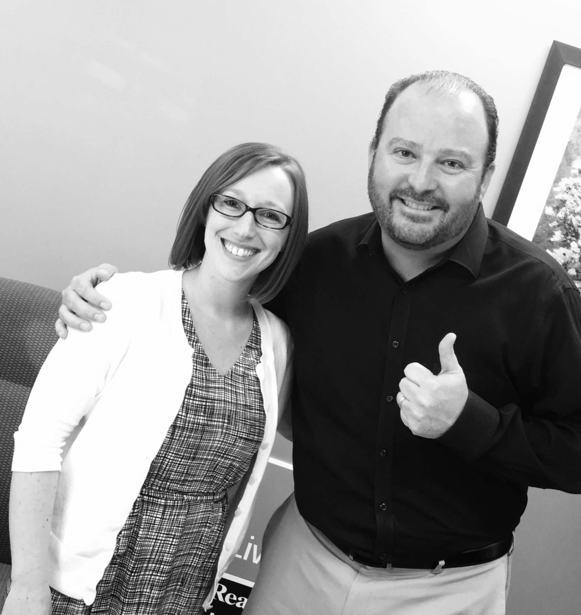 A man and a woman are posing for a picture and the man is giving a thumbs up.
