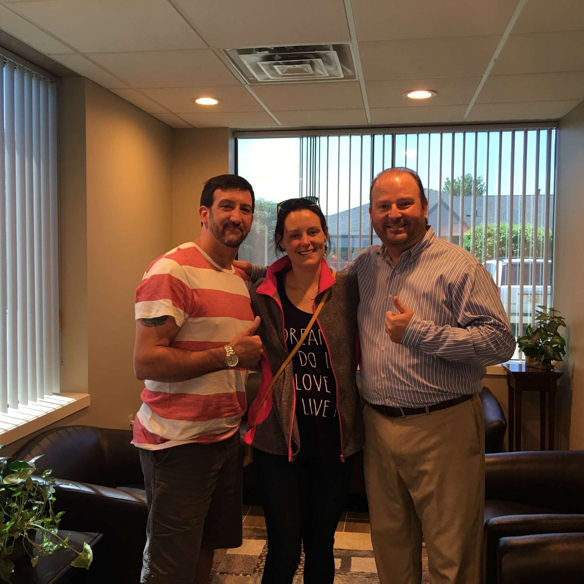 Three people are posing for a picture in a living room.