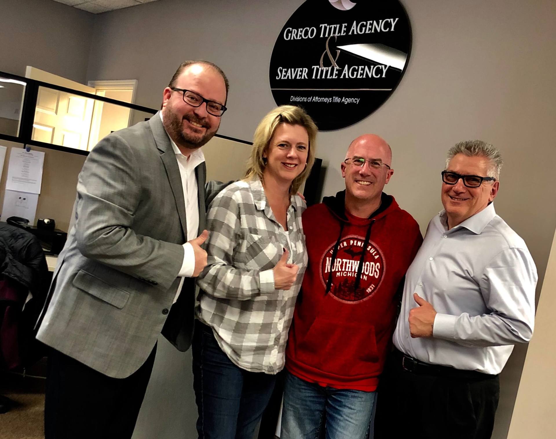 A group of people are posing for a picture in front of a sign that says title agency.