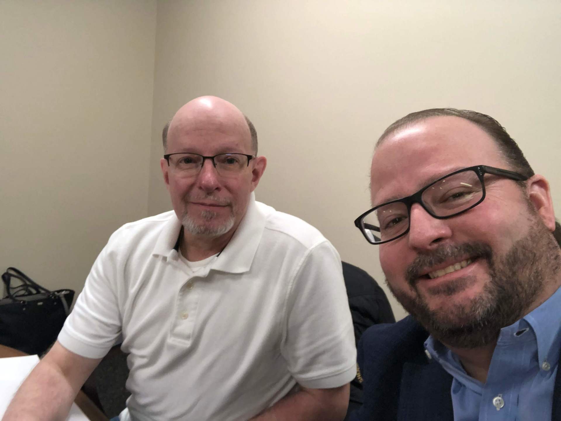 Two men wearing glasses are posing for a picture together.