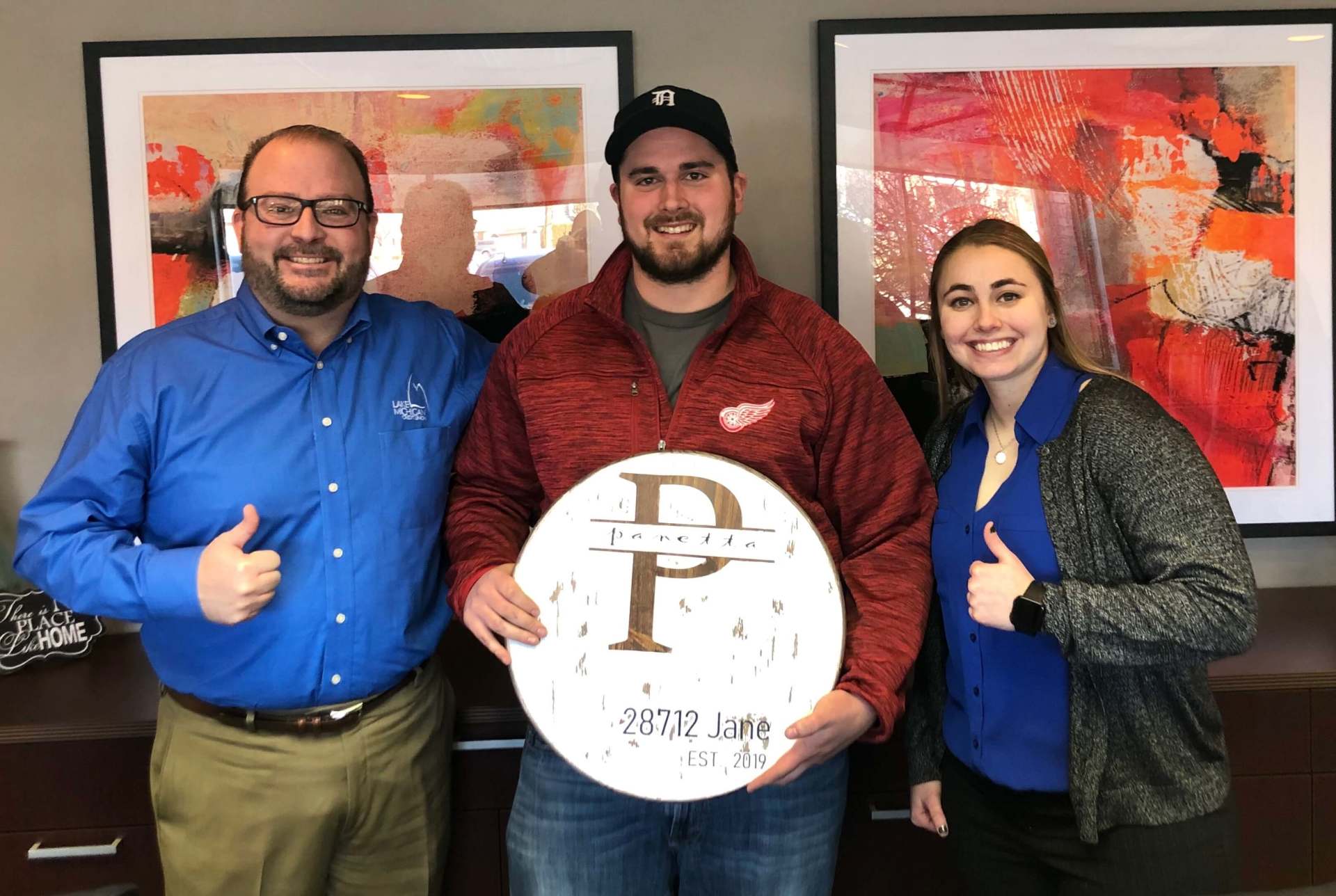 A man and two women are standing next to each other holding a sign with the letter p on it.