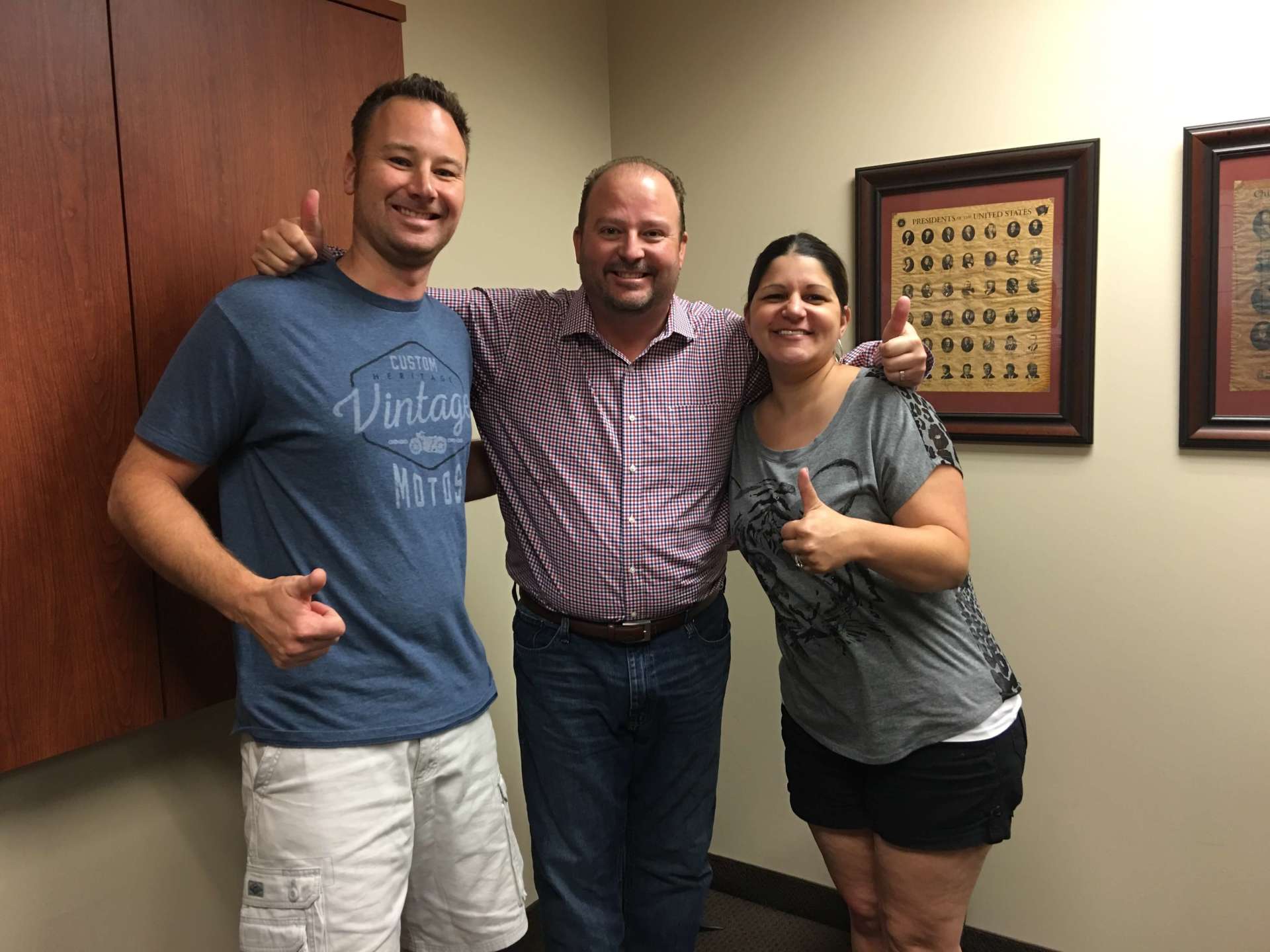 A man and two women are posing for a picture in a room.