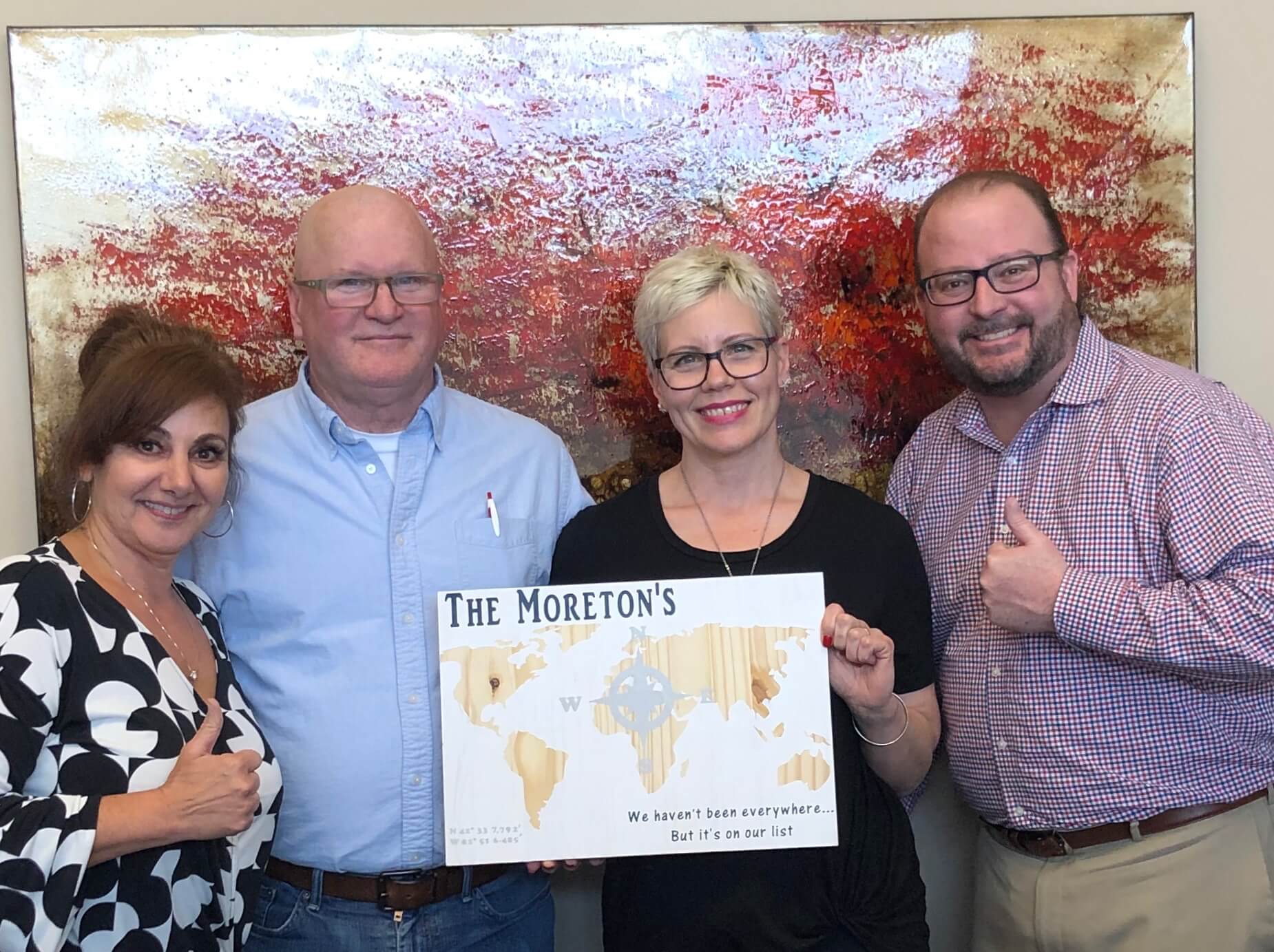 A group of people are standing next to each other holding a map of the world.