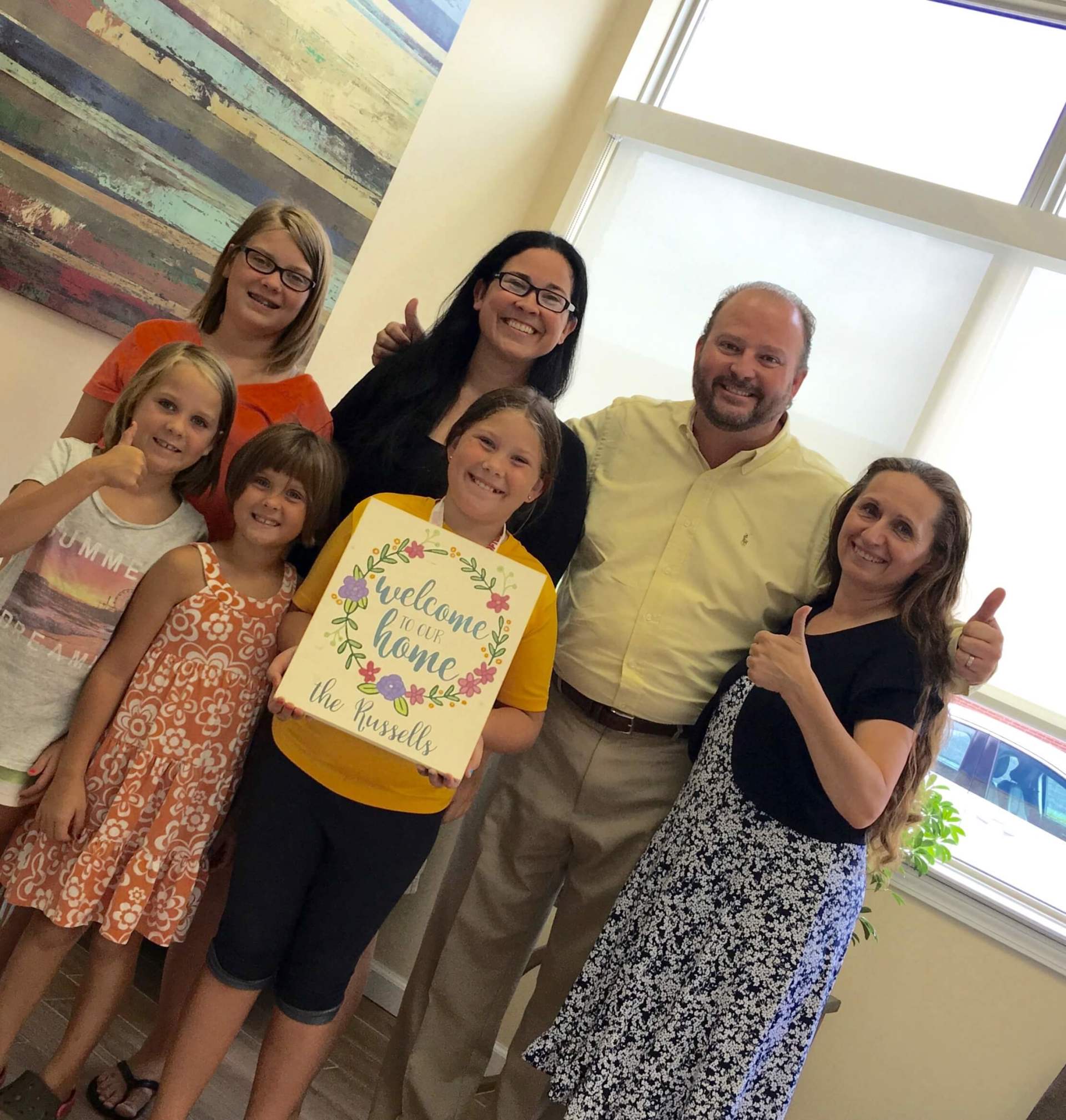 A group of people holding a sign that says welcome to our home.