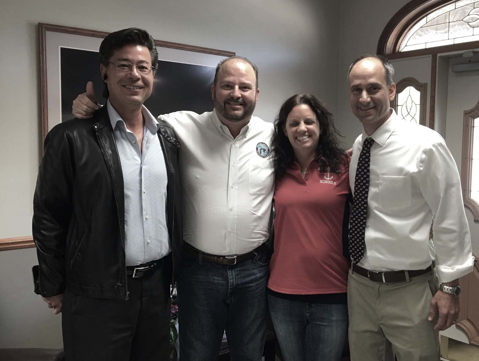 Three men and a woman are posing for a picture together.