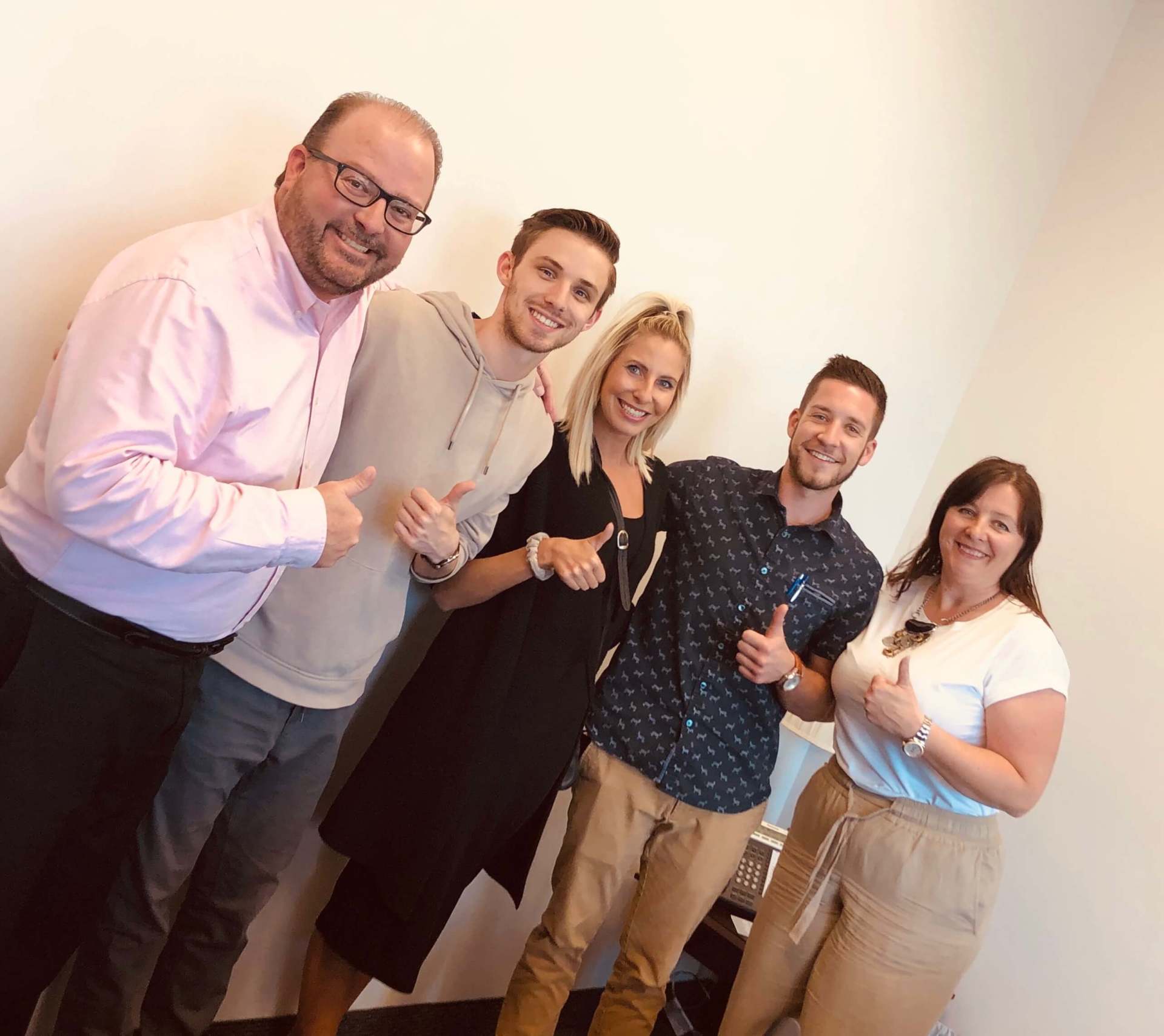 A group of people are posing for a picture and giving a thumbs up.