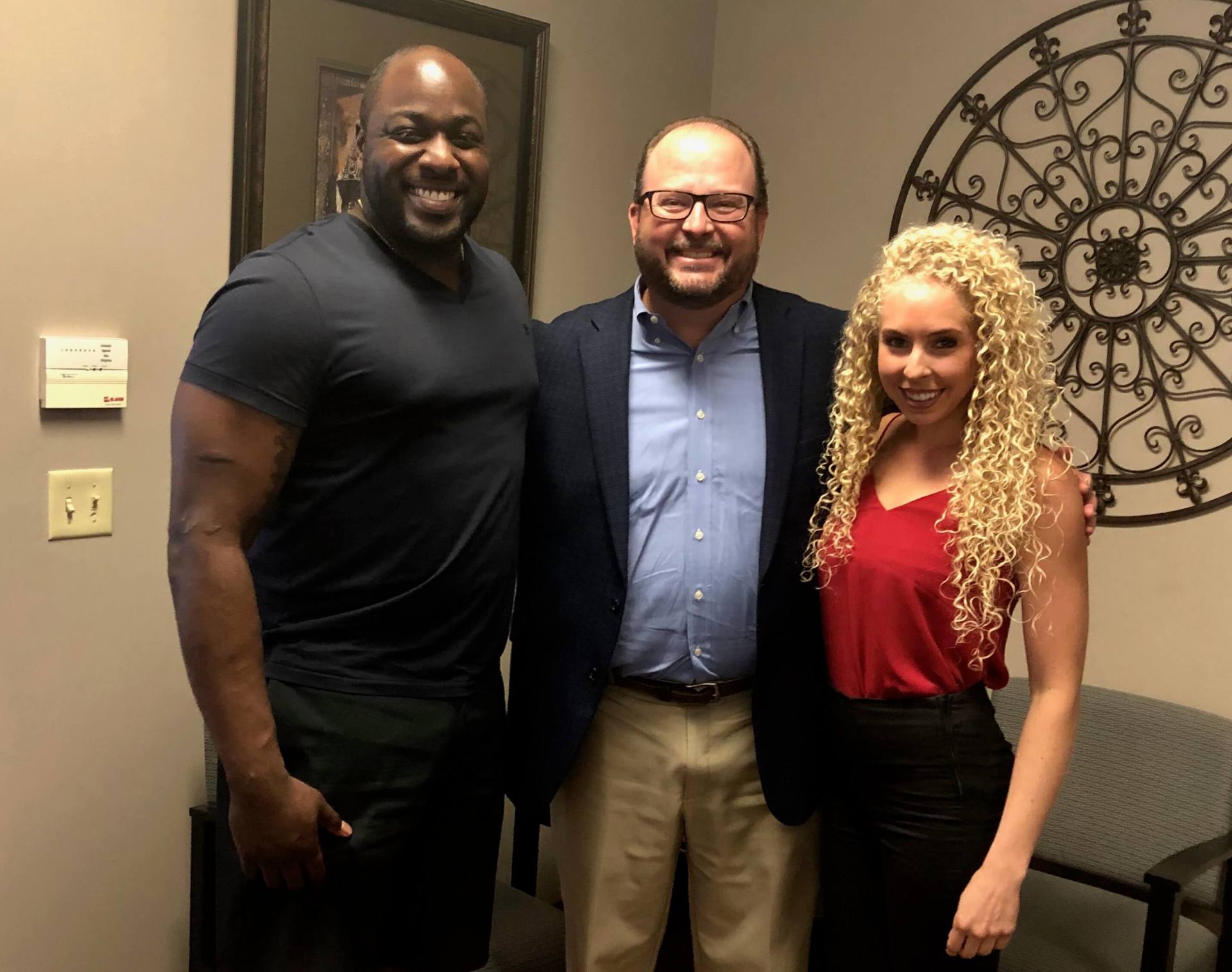 Two men and a woman are posing for a picture in a room.