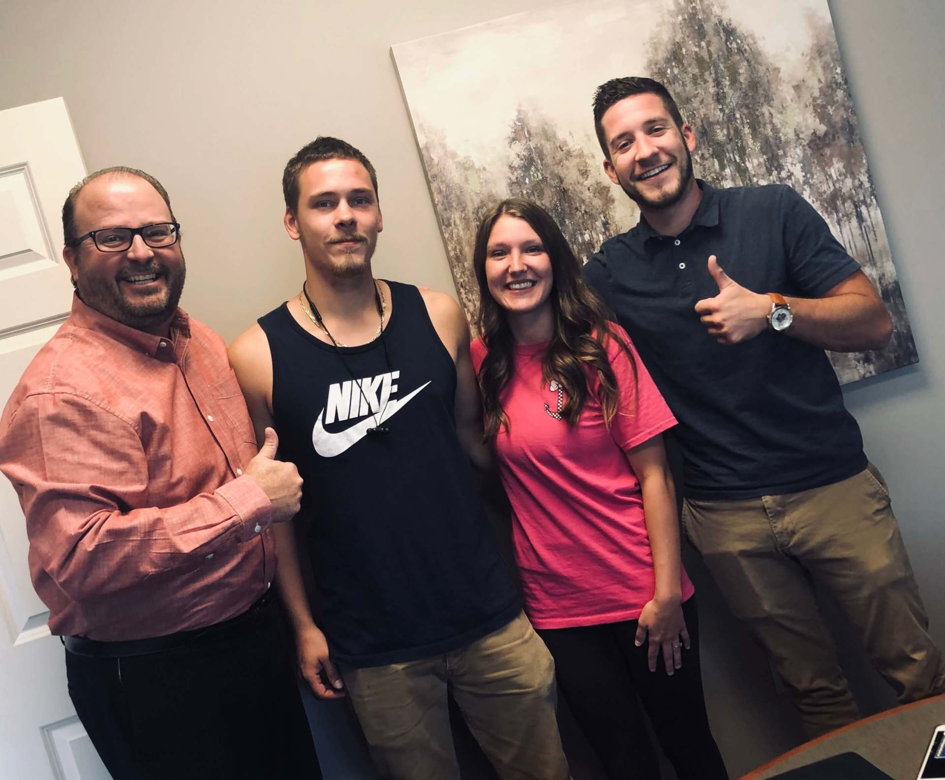 A group of people are posing for a picture and one of them is wearing a nike tank top.