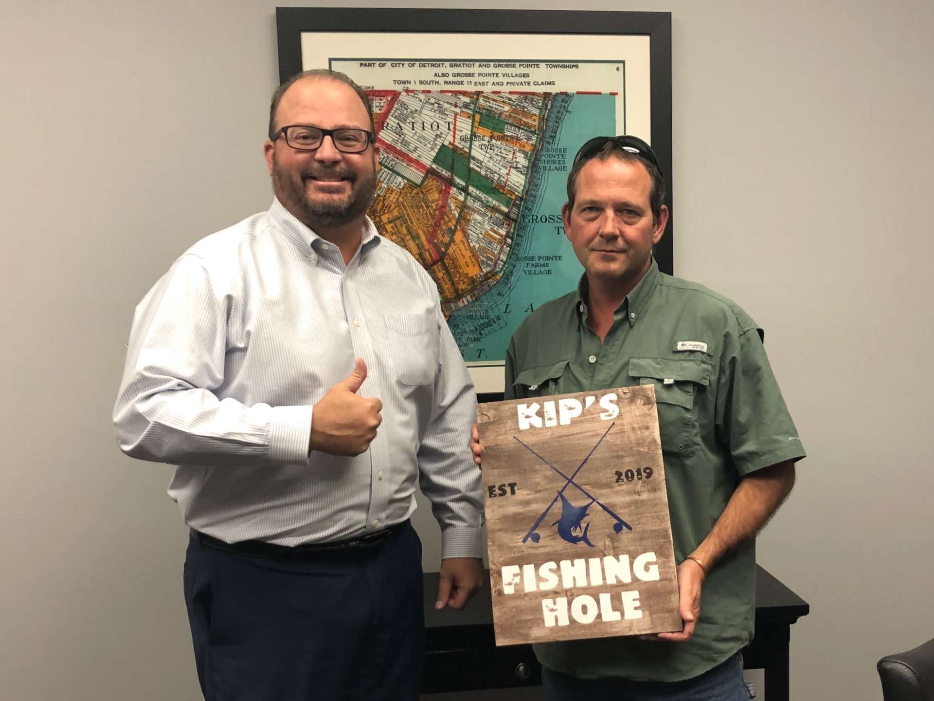 Two men are standing next to each other holding a sign that says fishing hole.