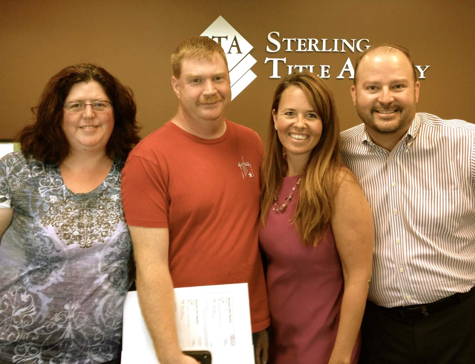 A group of people posing in front of sterling title agency.