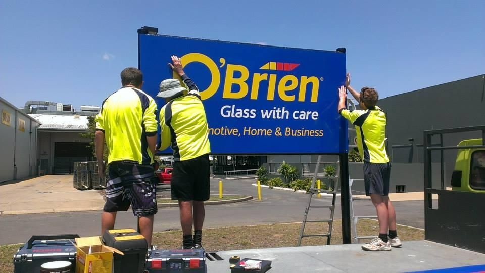 Three Men Are Installing a Sign for O'brien Glass with Care — Signmax Bundaberg In Kensington, QLD