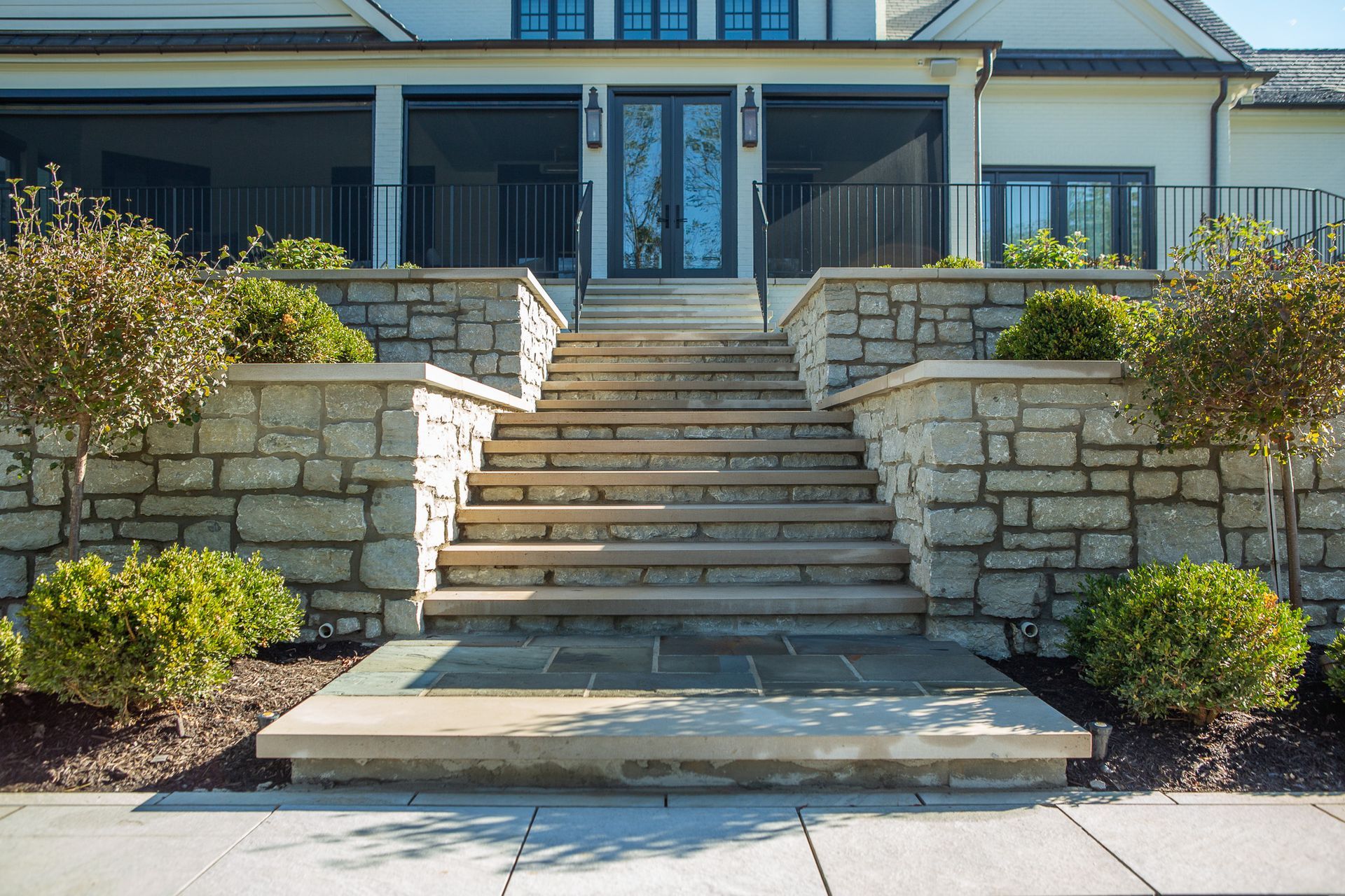Stone steps leading to a house entrance with stone walls and landscaping.