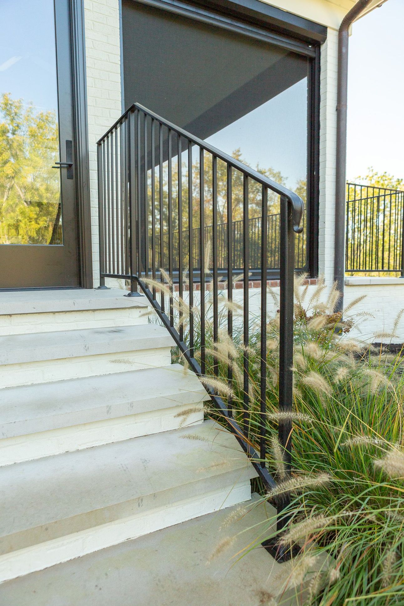 Park with green grass, trees, and a red sports area. A person sits on a bench. Buildings in the background.