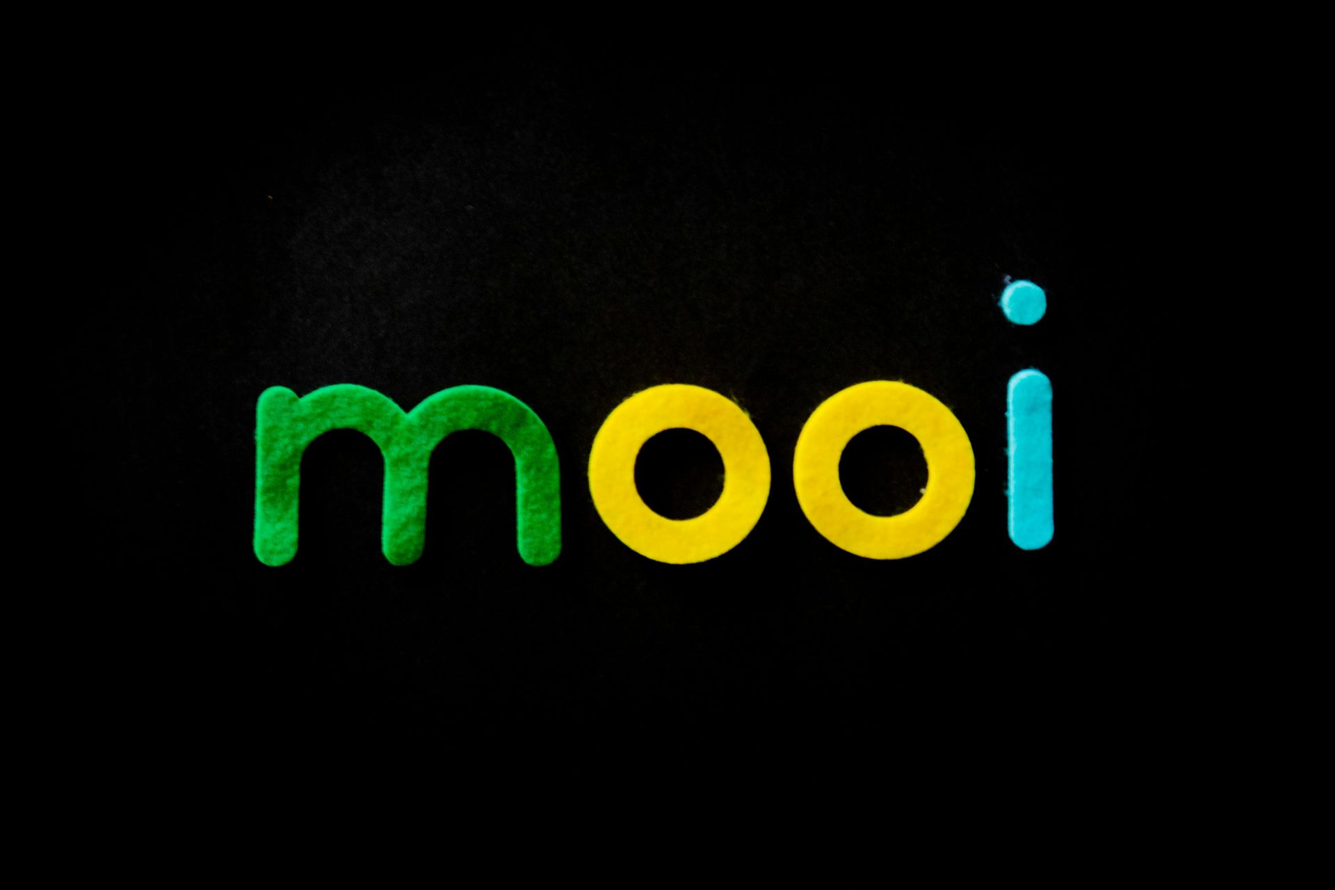 Mooi in colorful block letters: green 'm', yellow 'oo', blue 'i' on black background.
