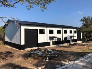 A black and white building is sitting in the middle of a dirt field.