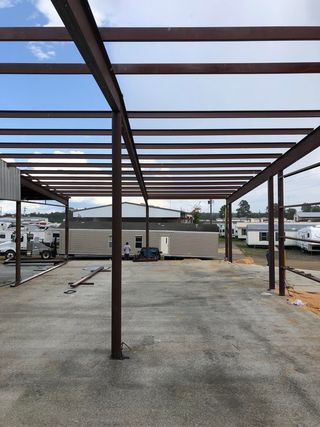 A metal structure is being built in a parking lot.