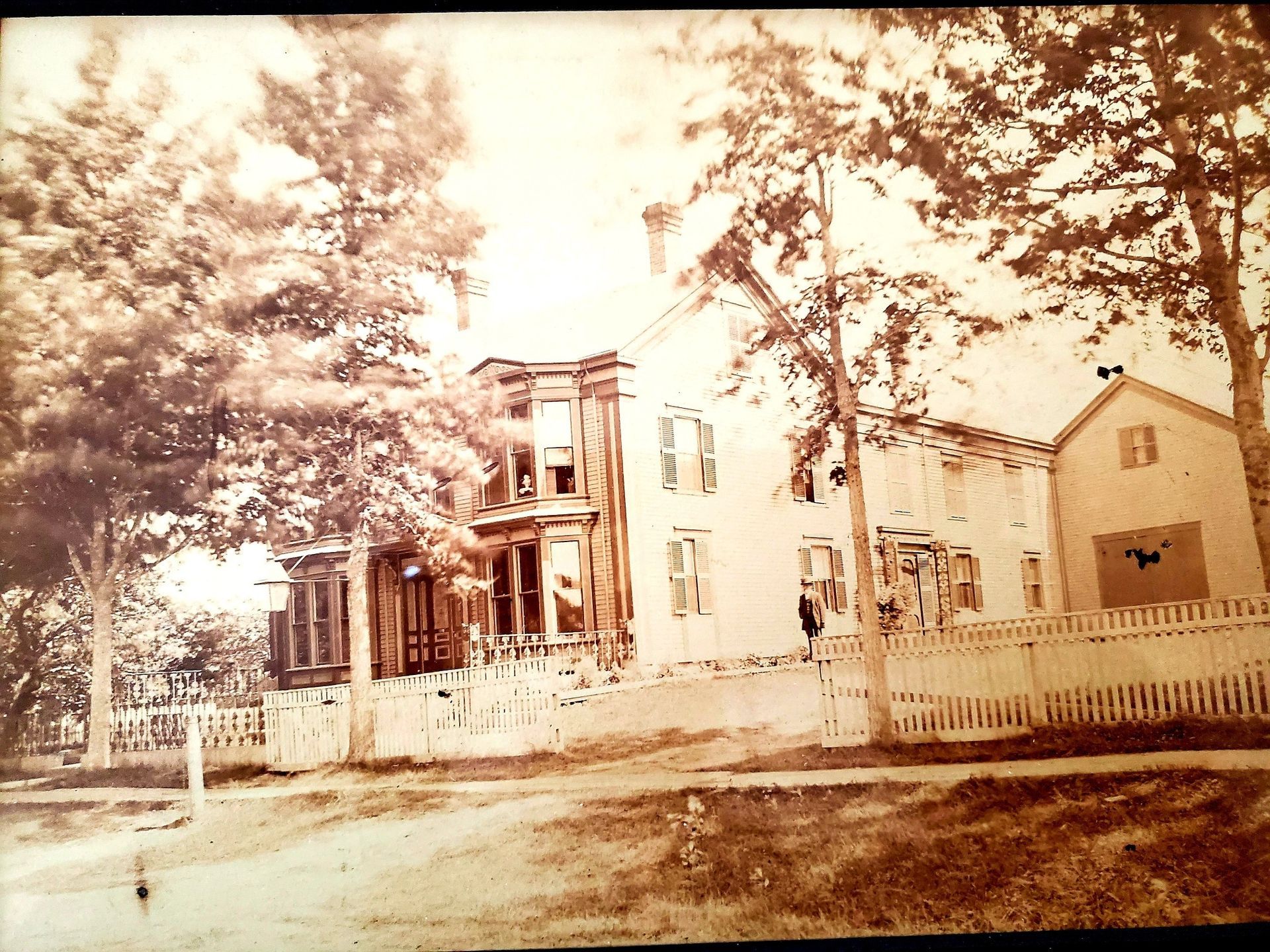 A black and white photo of a house with a white picket fence