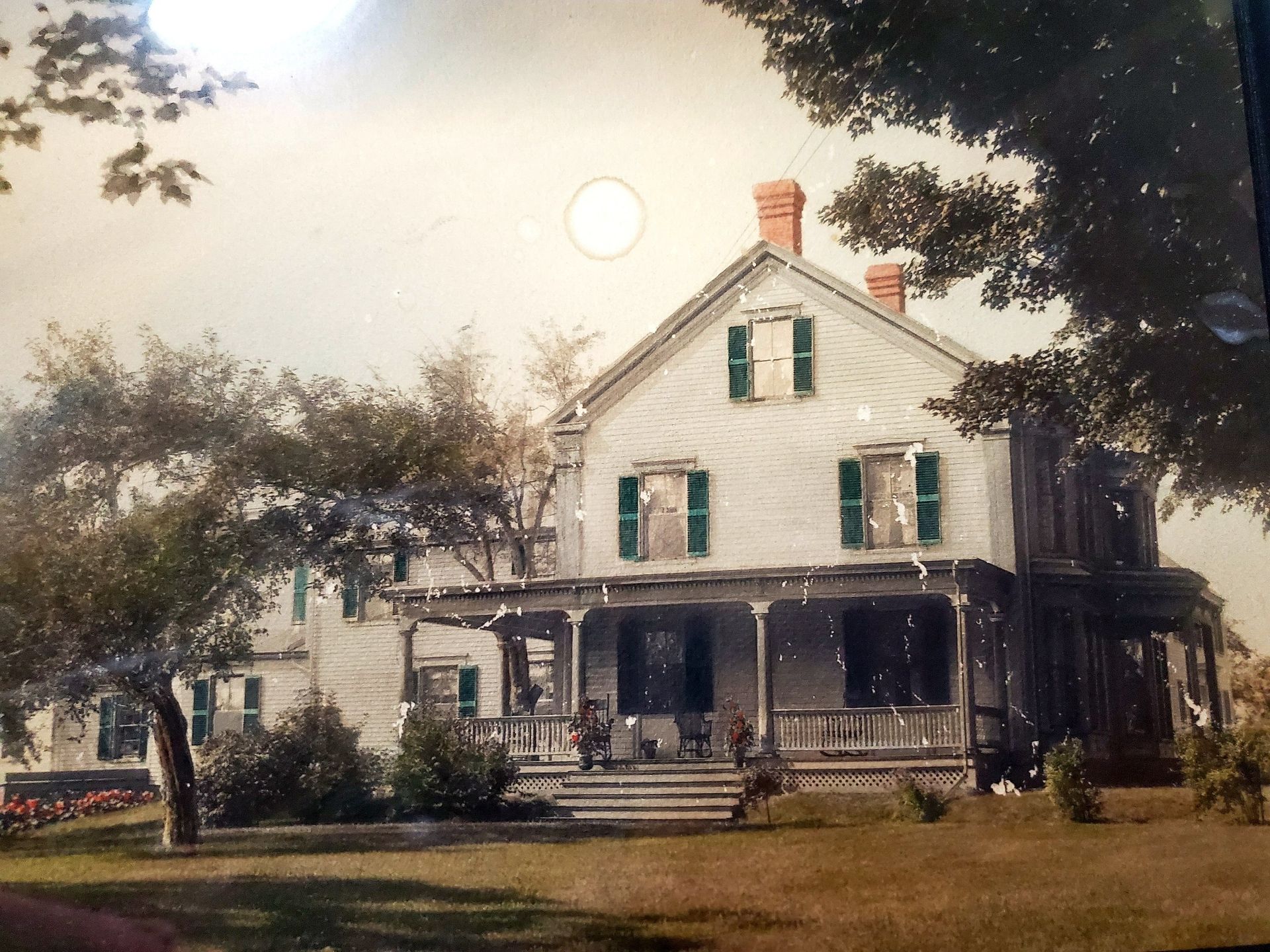 An old photo of a house with green shutters