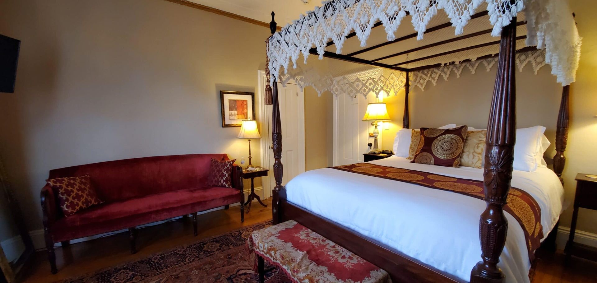 A bedroom with a four poster bed and a red couch